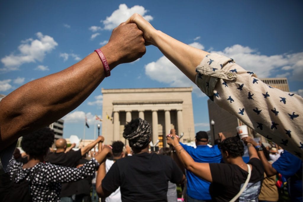 BALTIMORE, MD - MAY 03: People hold hands during a rally lead by faith leaders in front of city hall calling for justice in response to the death of Freddie Gray on May 3, 2015 in Baltimore, Maryland. Gray later died in custody; the Maryland state attorney announced on Friday that charges would be brought against the six police officers who arrested Gray. (Photo by Andrew Burton/Getty Images)